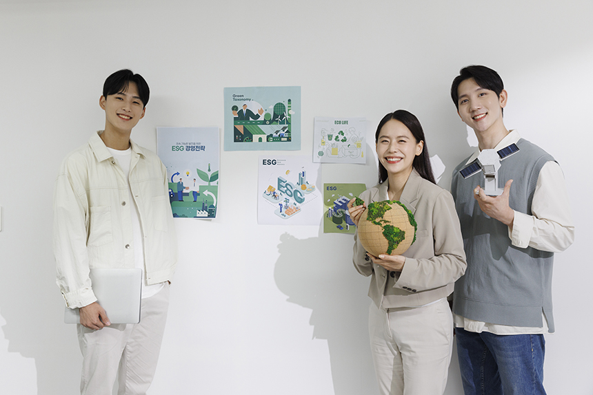 환경과 관련된 포스터를 붙인 벽면 앞에서 지구본을 들고 웃고있는 청년들의 모습.