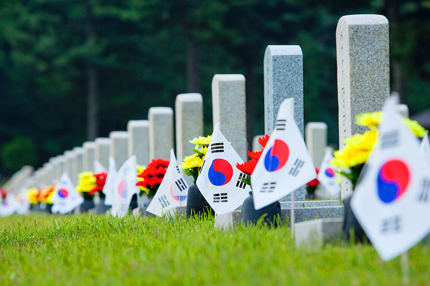 국가유공자들의 비석들과 그 앞에 놓인 헌화, 태극기