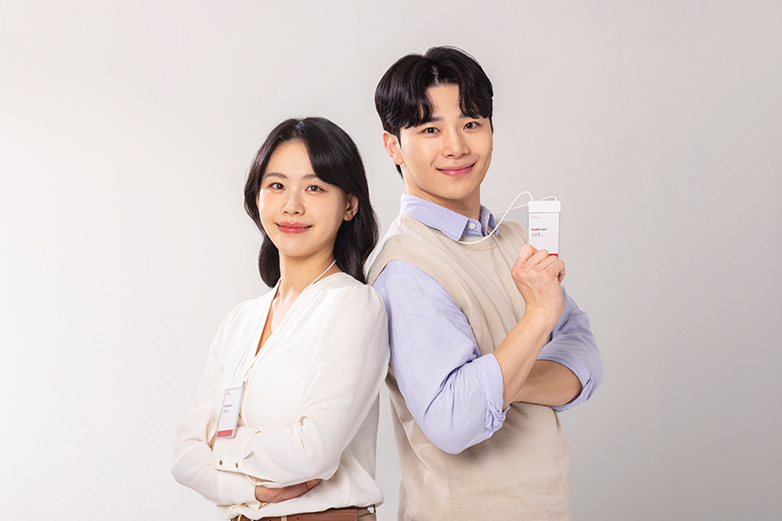 사원증을 착용하고 등을 맞대고 선 청년 나잇대의 여성과 남성.