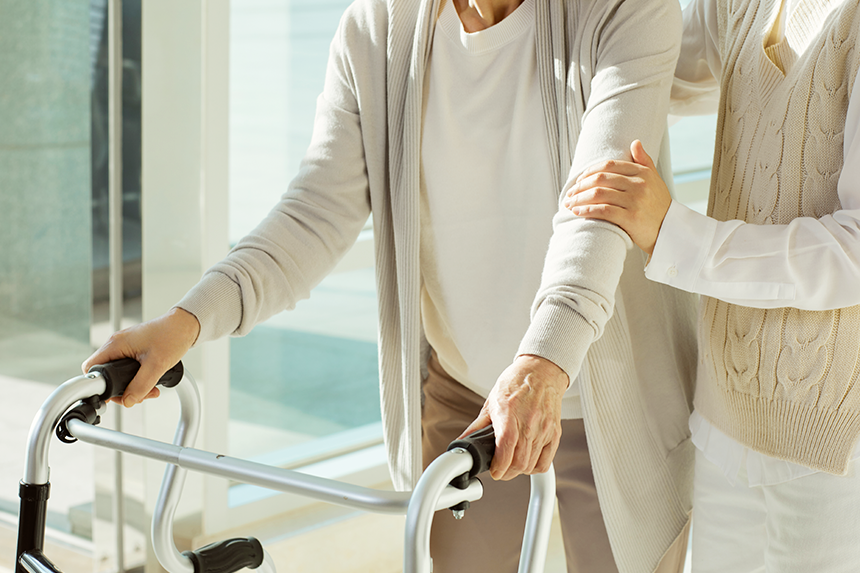 보행기를 밀고있는 노인과 옆에서 그를 부축해주는 사람