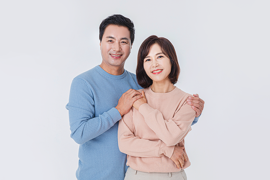 밝게 웃으며 서로를 껴안고 있는 캐주얼한 옷차림의 중년 부부