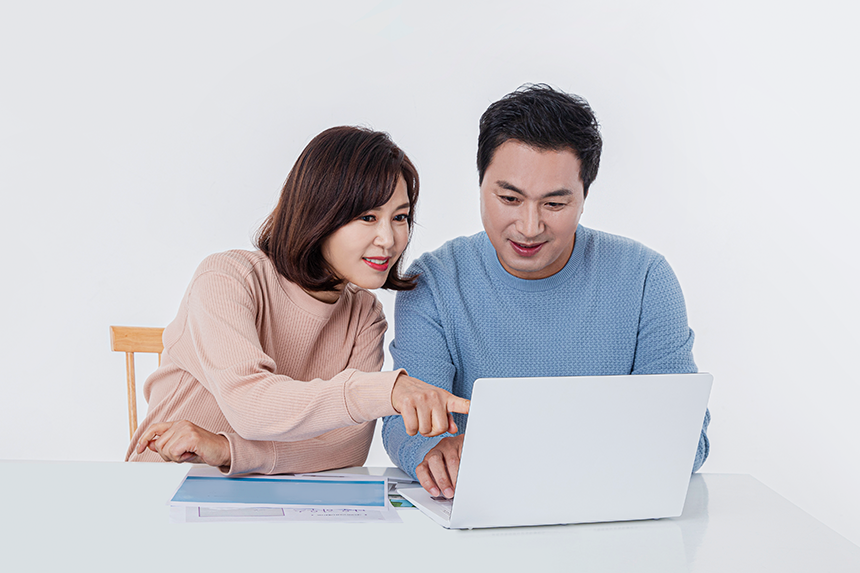 책상에 앉아 노트북 화면을 나누어 보고있는 중장년 남성,여성의 모습