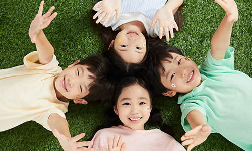 잔디밭에 누워 하늘을 바라보는 네명의 어린이