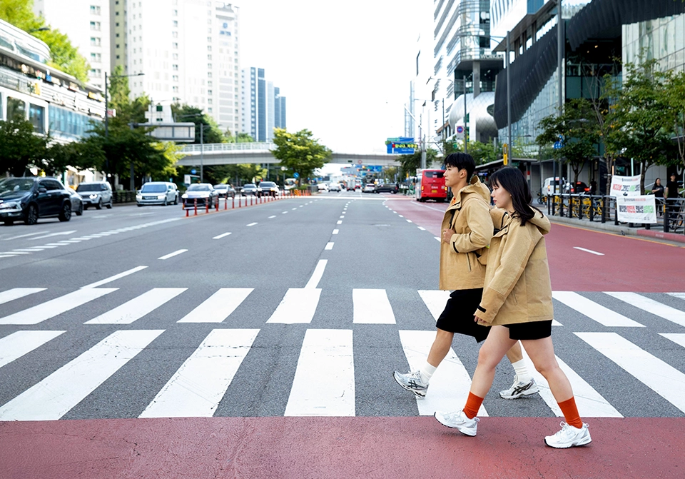 자켓을 입고 횡단보도를 걷는 두 남녀